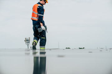 Construction worker inspects solar panel installation on rooftop during overcast day