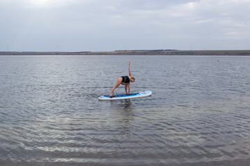 Woman exercising yoga. Poses with Sub board or Stand up Paddle board