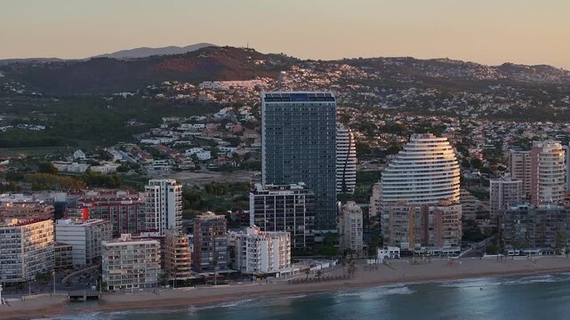 Amazing aerial view about coastal cityscape of Calp under evening light with distant mountains and local Estimar hotels, Alicante, Spain.
