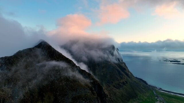 Midnight aerial of Mannen and coastal peaks wrapped in fog between Utakleiv and Haukland in Lofoten
