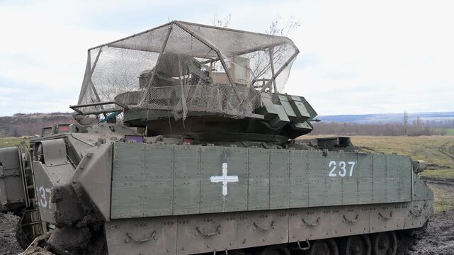 A US-made M2 Bradley IFV in Ukrainian service, showing its dual identity. The medical cross marks it for casualty evacuation, while the 'cope cage' defends against drones.
