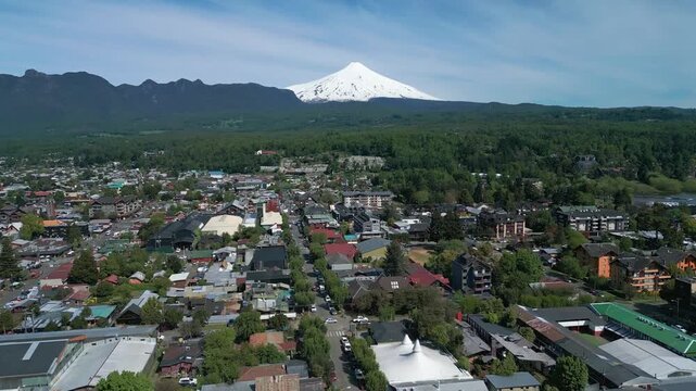 Flying above Pucon's town center, revealing Villarrica volcano and surrounding landscape on a clear day.