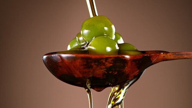 Super Slow Motion of Green Olives in Wooden Spoon with Pouring Oil . Filmed on High Speed Cinematic Camera at 1000 FPS