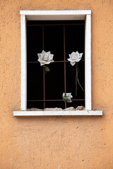 There is a beautiful window adorned with three lovely white roses in it