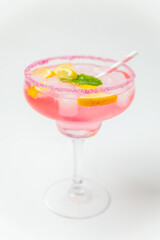 A cold pink refreshing drink with lemon and mint, chilled with ice cubes, decorated with a pink sugar rim. The best summer drink, rose lemonade on white background.
