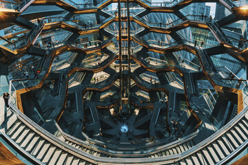 New York, United States - 17 February 2024: View of the Vessel, a hive of copper-toned stairs that spiral upwards, reflecting the surrounding city's steely skyscrapers.
