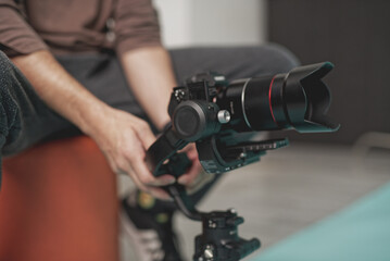 Person adjusts professional camera equipment while sitting in a modern indoor space during a collaborative project