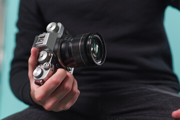 Person holding a modern camera with a lens in a casual setting, focused on photography and capturing moments