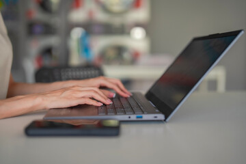 Female hands typing on a notebook in a laundromat. Working remotely while doing laundry. Casual productivity and flexible workspace theme.