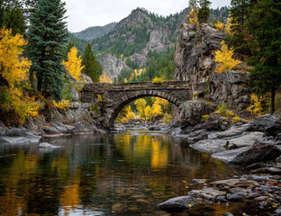 Fototapeta premium Stone arch bridge over a river surrounded by autumn foliage and mountains