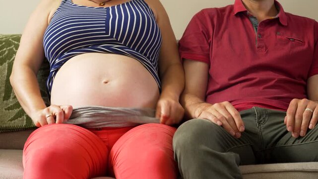 Expecting Couple Relaxing at Home, Husband Feels Baby Moves in Pregnant Wife&rsquo;s Belly