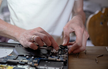 Man repairing laptop with tools on table, computer maintenance concept