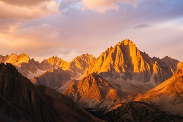 Naklejka premium Golden Sunset Over Rugged Mountain Peaks – Dramatic Landscape with Clouds and Shadows 