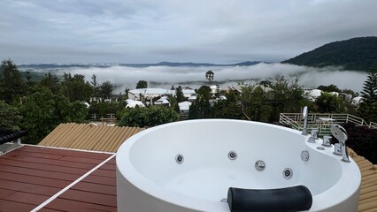 Phetchabun, Thailand, Outdoor jacuzzi with mountain view surrounded by fog, trees and white dome tents at Stratus Resort, Khao Kho.