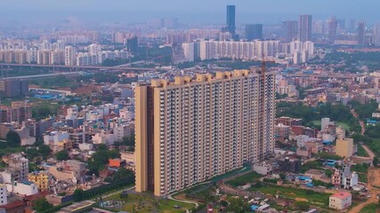 Aerial drone shot decending near under construction building with crane on top with delhi cityscape in the distance showing development in Noida, Chennai, Mumbai - Powered by Adobe