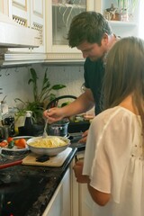 A couple cooks pasta together in their kitchen, sharing a moment of culinary teamwork and domestic bliss.