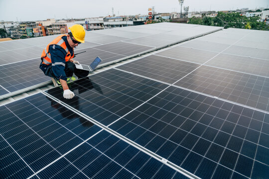 Technician performs maintenance on solar panels on a rooftop in an urban area during the day