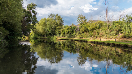 Aerial view of the tranquil River Wey, its waters mirroring the lush greenery under a sky touched with clouds, Guildford, Surrey, United Kingdom.