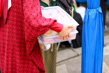 Naklejka premium close-up of a person's hand carrying a food box containing donuts
