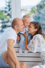 Fototapeta premium Family enjoying a joyful moment with their son while seated indoors in natural light