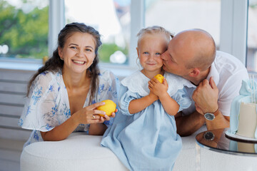 Family enjoying a joyful moment with their daughter while holding lemons indoors