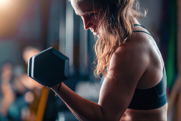 Biceps training with dumbbells engages a woman, lifting weights to build strength during a focused gym session.