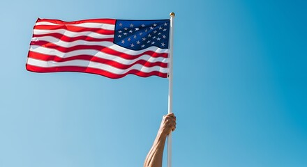 American Flag Waving in the Breeze Held by Hand Against Clear Blue Sky