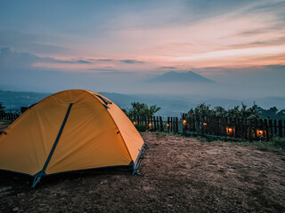 beautiful landscape of a mountain sunrise with a tent at a campground in the morning