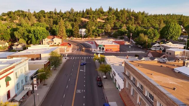Susanville, California, United States, aerial view of the main street lined with buildings, trees, and mountains bathed in the golden light of the early morning sun.