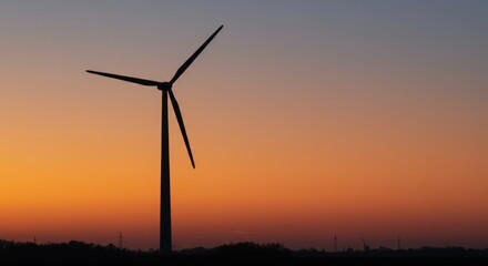 Fototapeta premium Silhouette of a lone wind turbine at dusk against a vibrant orange and purple gradient sky