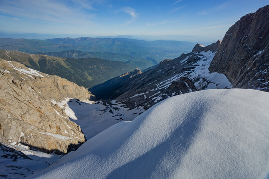 Aerial view of sunlit snow blankets rugged mountain peaks, casting long shadows across the landscape, 4 Rodias, Litochoro, Larisa, Greece.