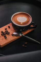 Coffee in black cup on wooden table in coffee shop with lighting background