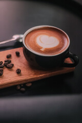 Coffee in black cup on wooden table in coffee shop with lighting background