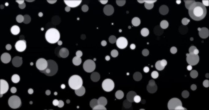 White and black particle bokeh floating in black background. Loop