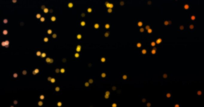 Golden particles bokeh floating in black background. Loop