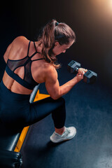 Exercising with weights, a woman places weights on a barbell, preparing for training to build strength in a focused gym setting.
