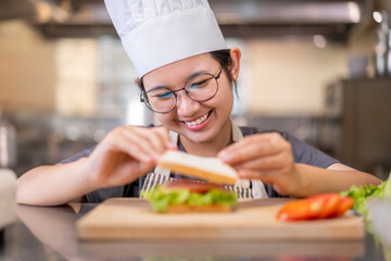 Smiling Young Asian Female Chef Preparing Sandwich in Kitchen