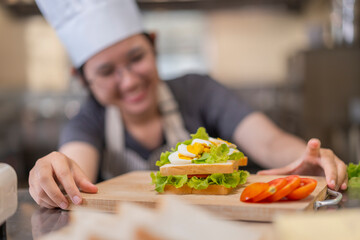 Smiling Young Asian Female Chef Making Sandwich