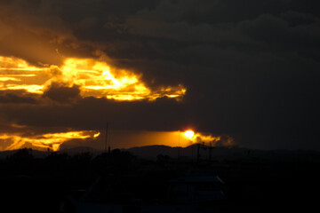 Golden sunset painting the clouds over dark hills