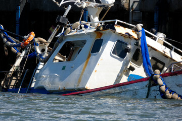 Sunken fishing boat partially submerged in harbor, maritime accident scene