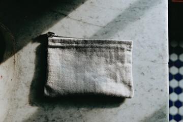 Light gray fabric zippered pouch on marble