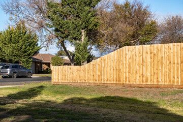 Newly built timber boundary fence in a suburban Australian neighborhood, featuring a curved design that is lower at the front near the driveway and higher toward the rear for added privacy.