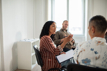 Young woman leading group therapy session in modern counseling center