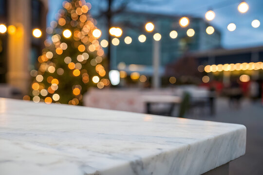 Blurred festive christmas tree with warm bokeh lights in an outdoor city setting, with a marble surface in the foreground