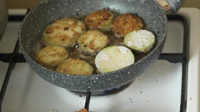 Frying zucchini pan. Breaded vegetable slices cooking in hot oil on a gas stove for homemade meal.