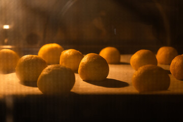 Golden sweet cookies baking in a hot oven, rising and spreading on a baking tray.