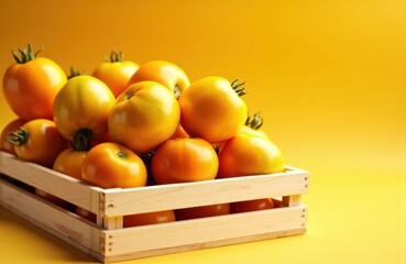 Fresh yellow tomatoes arranged in a wooden crate against a yellow background