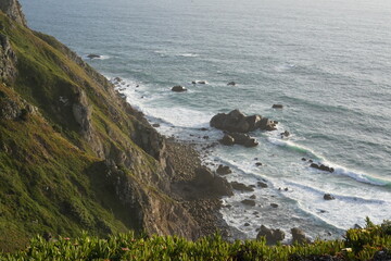 Coastal cliffs overlook rocky shoreline and waves near sunset in a serene natural landscape