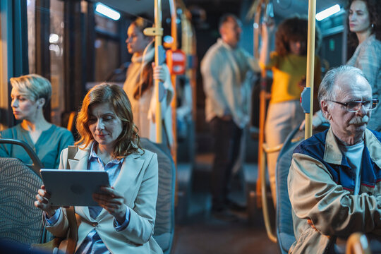 Businesswoman using digital tablet while riding public transport at night - Powered by Adobe