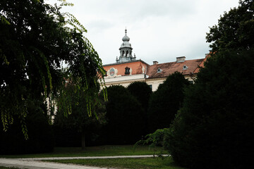 Fototapeta premium Partially hidden behind trees, the historic Sombor City Hall with its decorative dome is seen from a side view in Serbia.